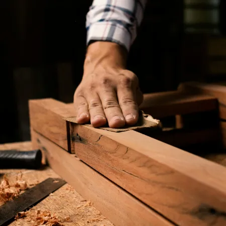 Mann schleift Holz mit Schleifpapier ab